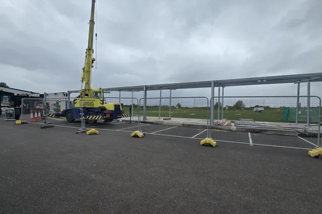 Mobile crane erecting the canopy steelwork over the driving-range bays, Moreton Hills Golf Centre entrance visible behind